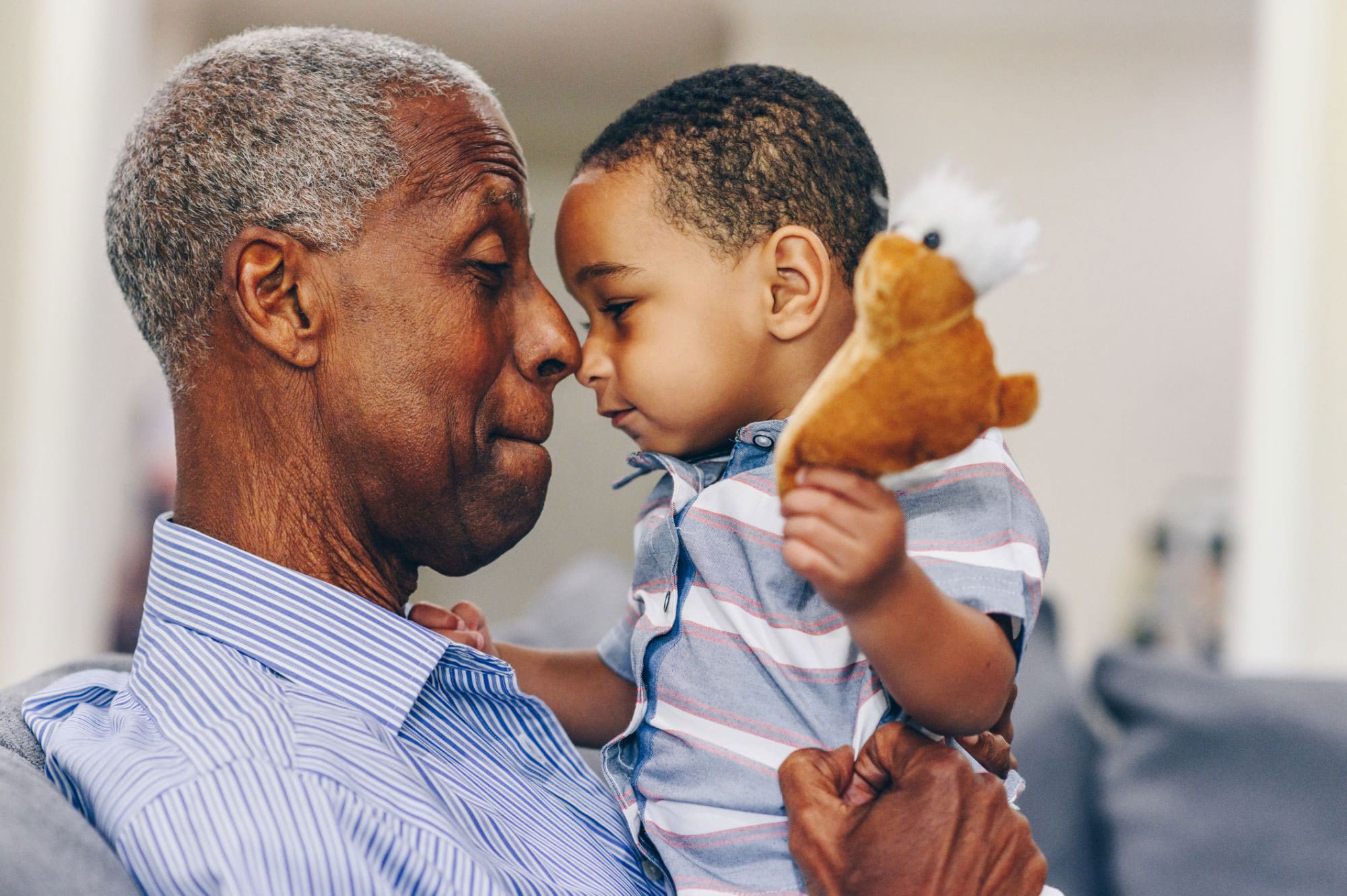 Senior man holding his toddler grandson and smiling