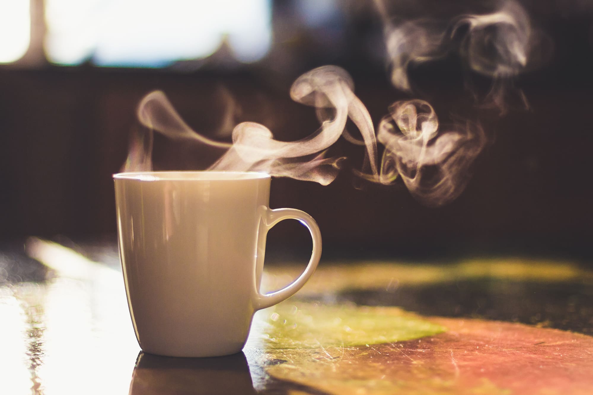 Close up of steaming cup of coffee or tea on vintage table - early morning breakfast on rustic background Cup of hot drink on the table