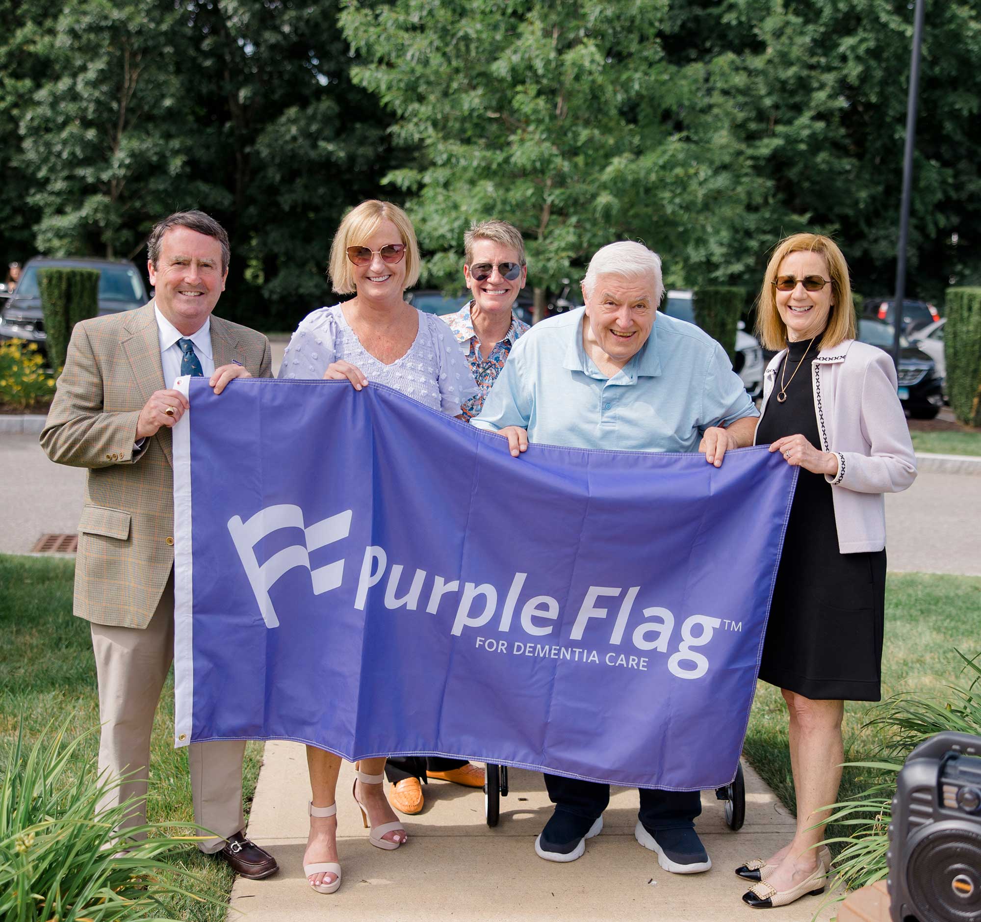 Bridges team and a Bridges resident holding up Purple Flag for Dementia Care
