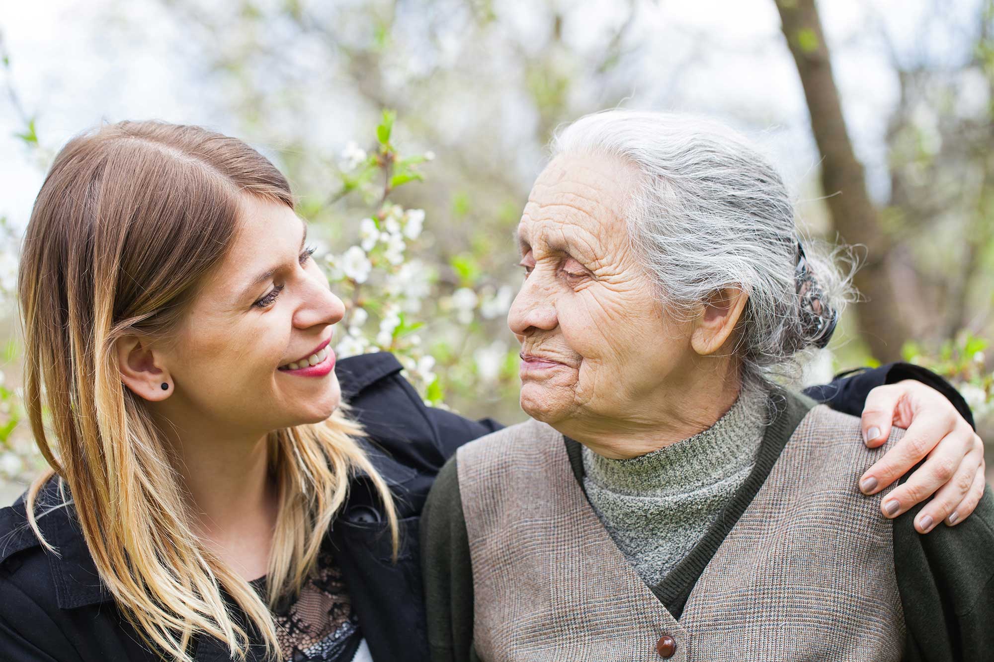 Picture of a happy elderly woman with her cheerful carer outdoor springtime