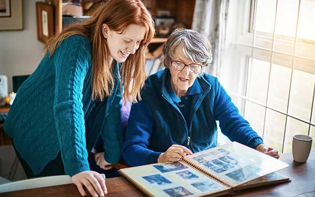 senior woman and her grand-daughter looking at an old photo album