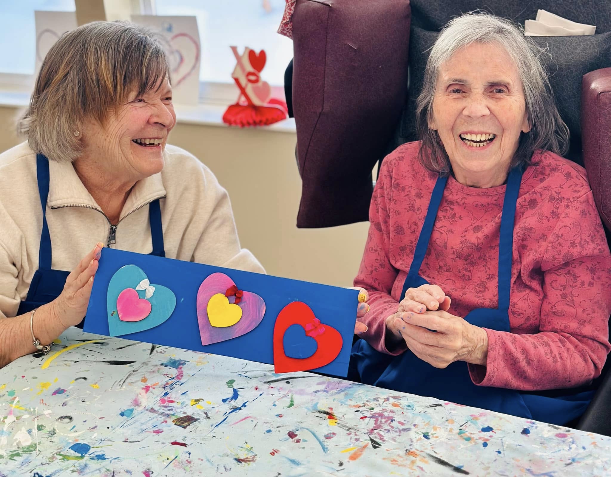 resident and caregiver smiling during a craft activity